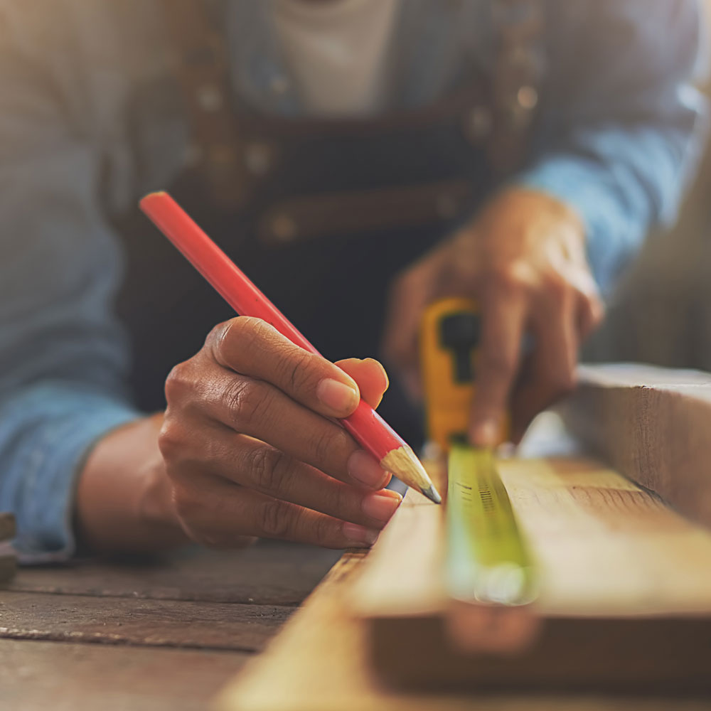 Close up of carpenter measuring and marking a piece of wodd.