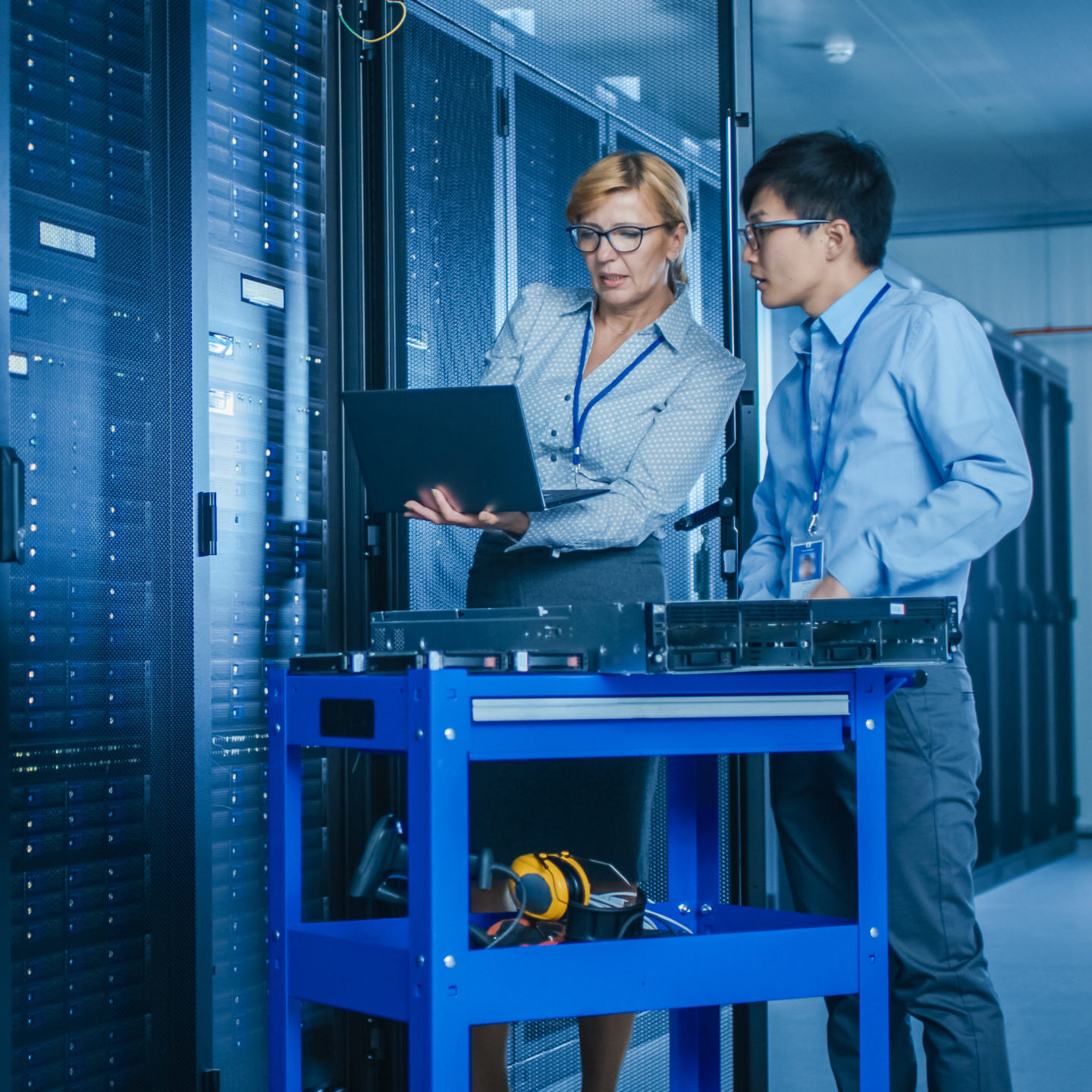 female and male colleague with a laptop in front of server towers