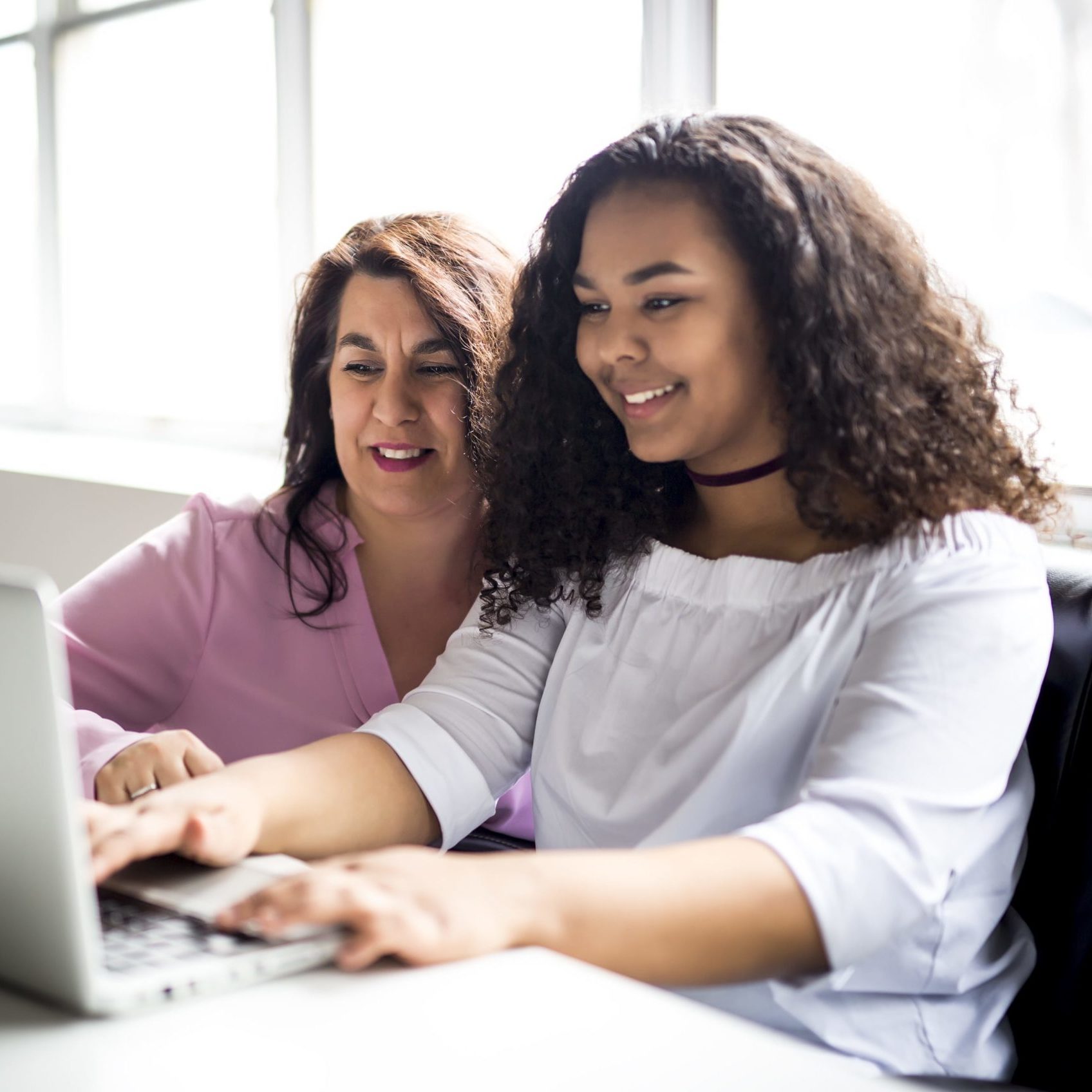 Woman in 40s and teenager looking at a laptop screen together